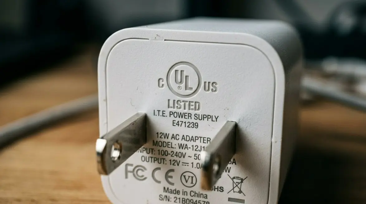 Close-up of a sleek 12W wall mounted power adapter featuring US-standard prongs and a visible UL certification mark on the back plate.